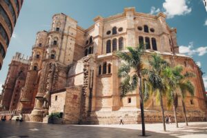 Fachada de la Catedral de Málaga rodeada de palmeras.